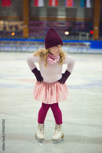 Pretty girl skates in a red cap, warm gloves and sweater