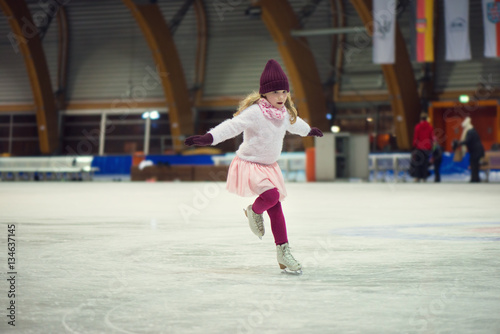 Pretty girl skates in a red cap, warm gloves and sweater