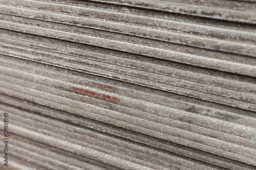 A side view on the Flat slate sheets stacked on each other. Material for construction. Close-up angle with blurred background