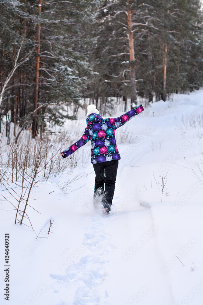 Girl goes through the snow in the winter in the forest