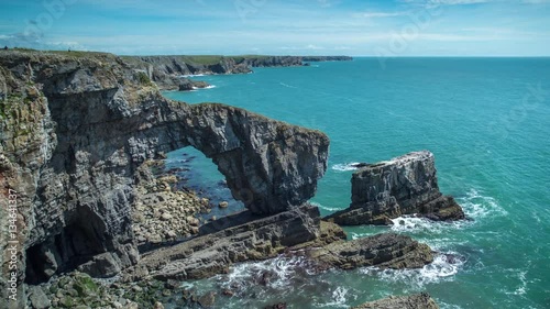 timelapse of the green bridge, a natural rock arch on the coast of pembrokeshire, wales, UK photo