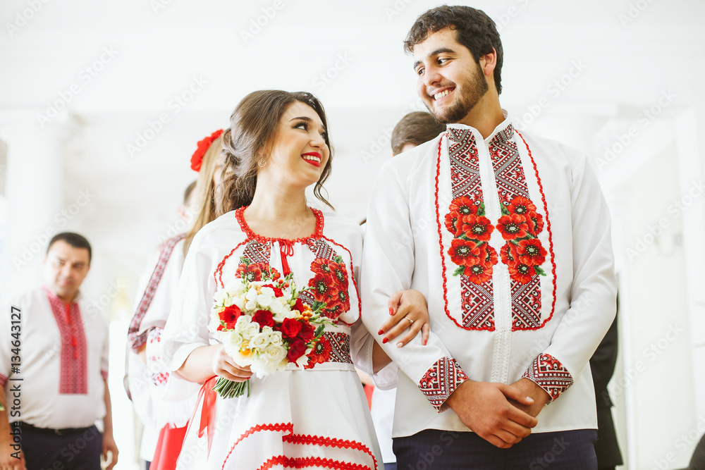 Obraz premium Lovely newlyweds in embroidered shirts look at each other before