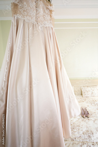 Look from behind cream dress and pink shoes standing on white be