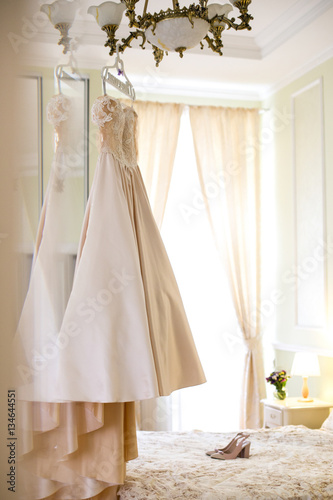 Look from behind the door at wedding dress hanging on chandelier