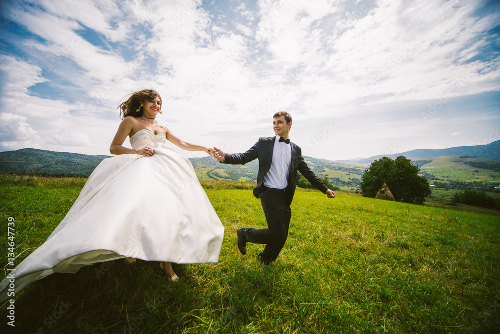 Bride and groom hold each other hands tightly running across the Stock  Photo | Adobe Stock