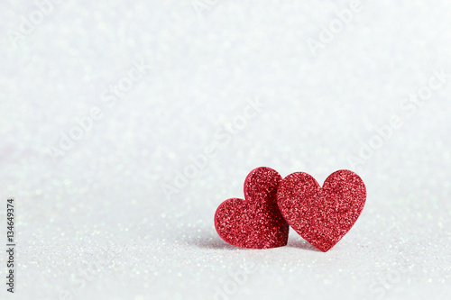 Two red heart shapes on white glitter bokeh light for valentines background