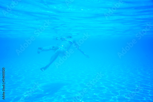 woman swimming in the pool view from under a water