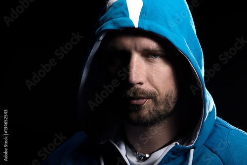 Young man with a toothpick with hoody in studio