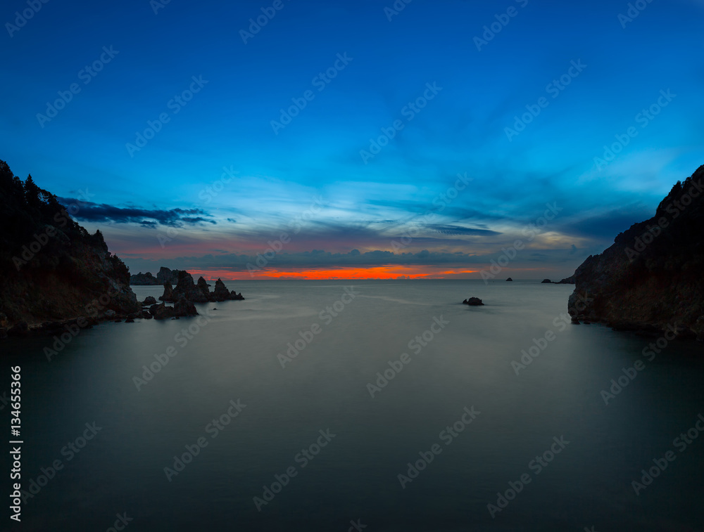 Long exposure seascape at sunrise. View of the cliff into the sea and distant islands. Paleokastrica. Corfu. Ionian archipelago. Greece.