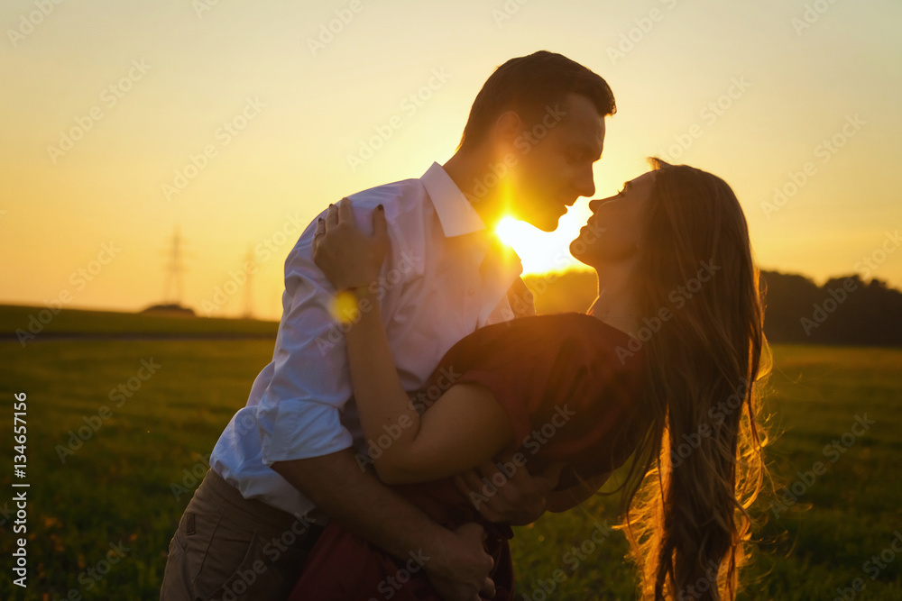 pasion couple kisses in field at sunset