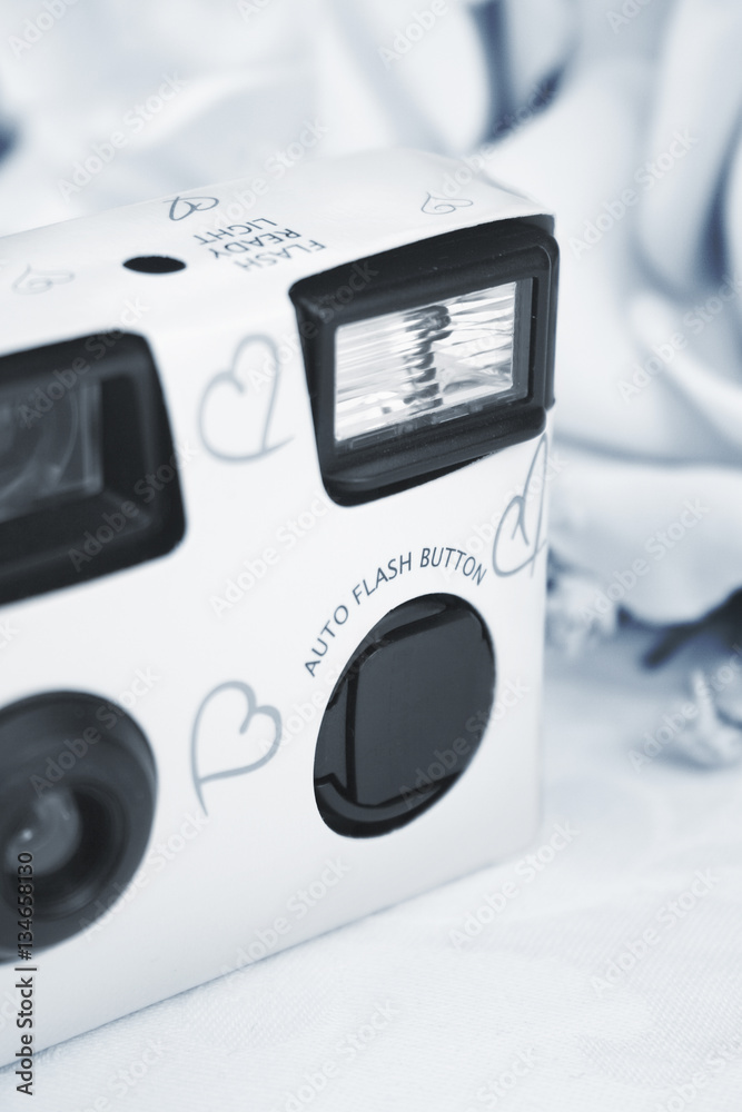 Fototapeta premium Disposable white wedding camera with silver hearts on the front.