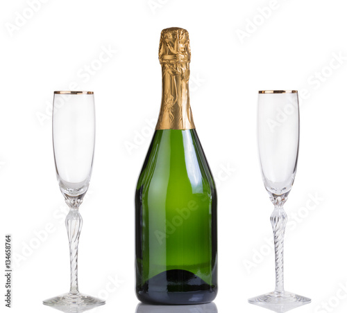 Unopened bottle of champagne and drinking glasses on white 
