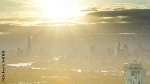 a sunset timelapse of the city of london skyscapers, zoomed in from a high vantage point far away. amazing sunrays are captured during this scene photo