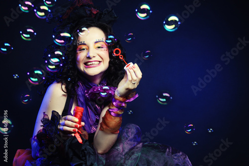 fashion model with creative make-up blowing soap bubbles. 
