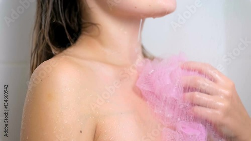 Closeup slow motion of young brunette woman lathering and washing at shower photo