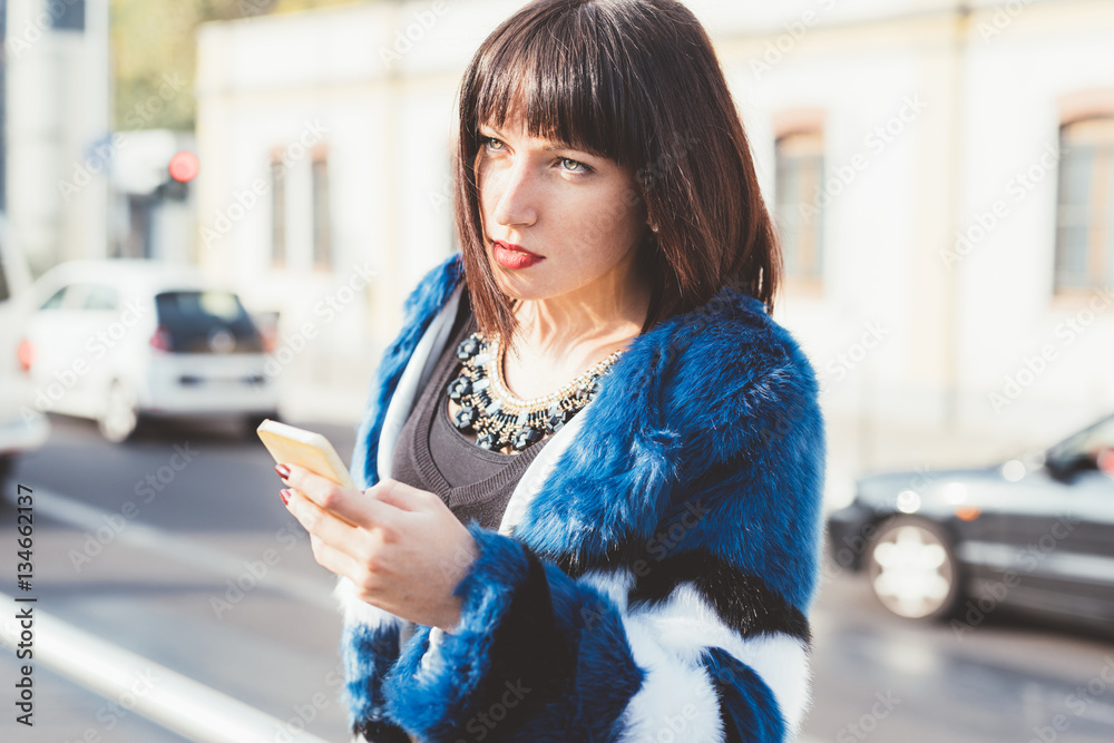 Young beautiful eastern black hair woman sitting on the floor, holding a smart phone looking down and tapping screen - technology, social network, communication concept Young beautiful eastern black hair woman sitting on the floor, holding a smart phone looking down and tapping screen - technology, social network, communication concept