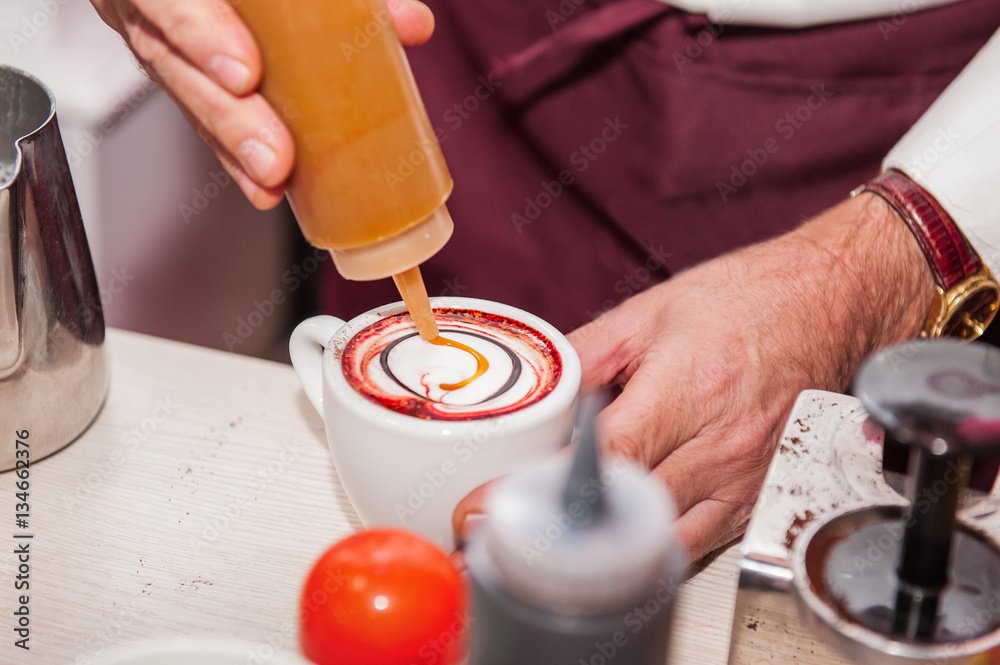 Close up barista making latte or cappuccino coffee art drawing with caramel syrup. Selective focus