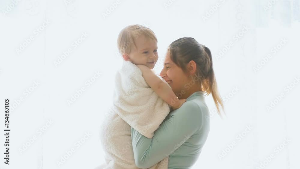 Happy young mother with her baby son posing at big window Happy young mother with her baby son posing at big window