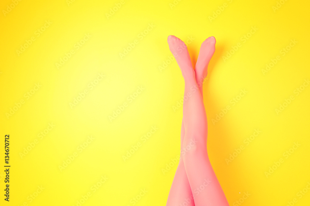 Female legs in pink stockings on color background Female legs in pink stockings on color background