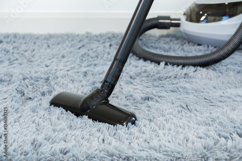cleaning carpet floor with vacuum cleaner in the living room
