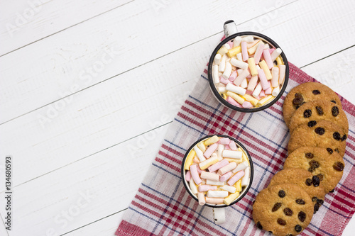 Two cups of hot cocoa  with color marshmallow and oatmeal cookie