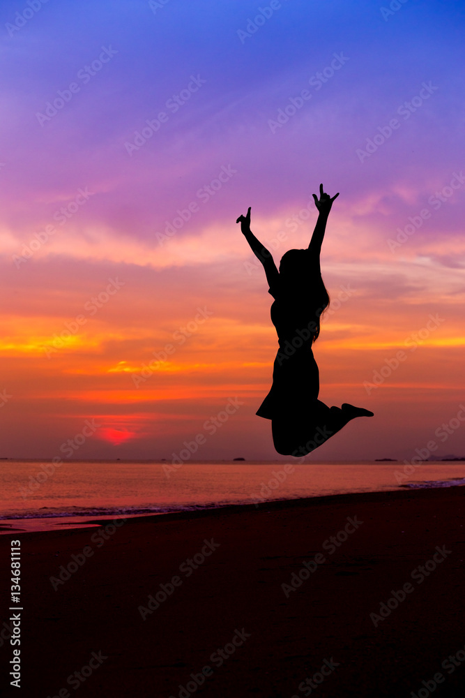 Silhouette of woman jumping with hands up and showing I LOVE YOU