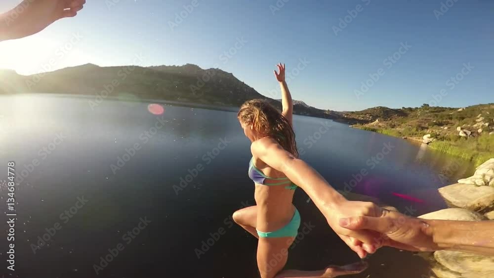 Couple holding hands while jumping into a lake