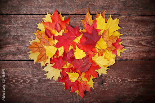 Colorful heart made of autumn leaves on a wooden background photo