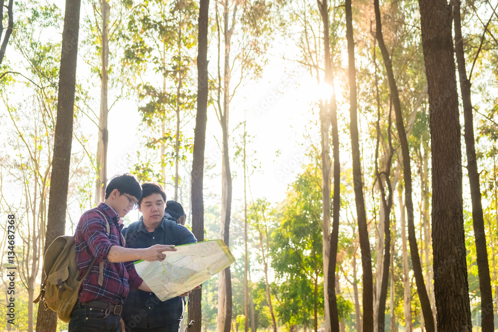 Hiking couple looking at map hiking in forest. Young interracial Hiking couple looking at map hiking in forest. Young interracial
