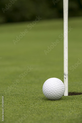 Golf ball close to pin and hole