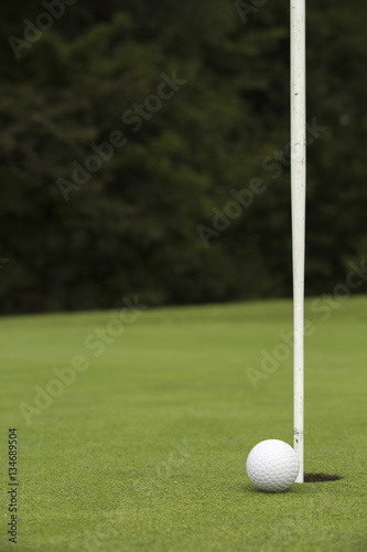Golf ball close to pin and hole