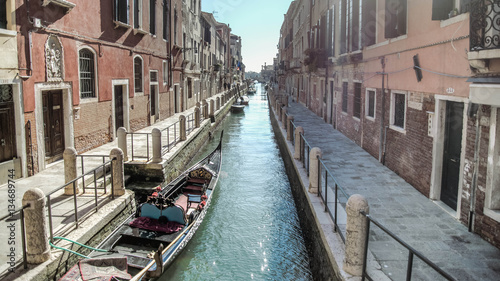 Venice, Italy - February 17, 2015: Classical picture of the venetian canals with gondola across the canal.