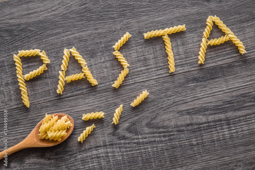 Word pasta created from pasta macaroni on the wooden table in the kitchen. Healthy eating and lifestyle. Word pasta created from pasta macaroni on the wooden table in the kitchen. Healthy eating and lifestyle.