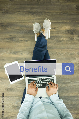 Young man sitting on floor with laptop and searching BENEFITS co