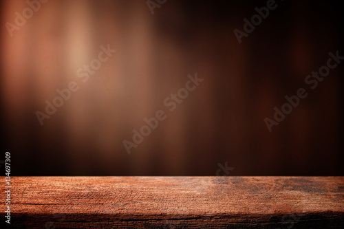 Old wood table with dark brown wall blurred background.