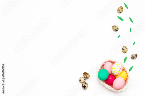 quail eggs and chicken colorful eggs in a pink basket on white background.