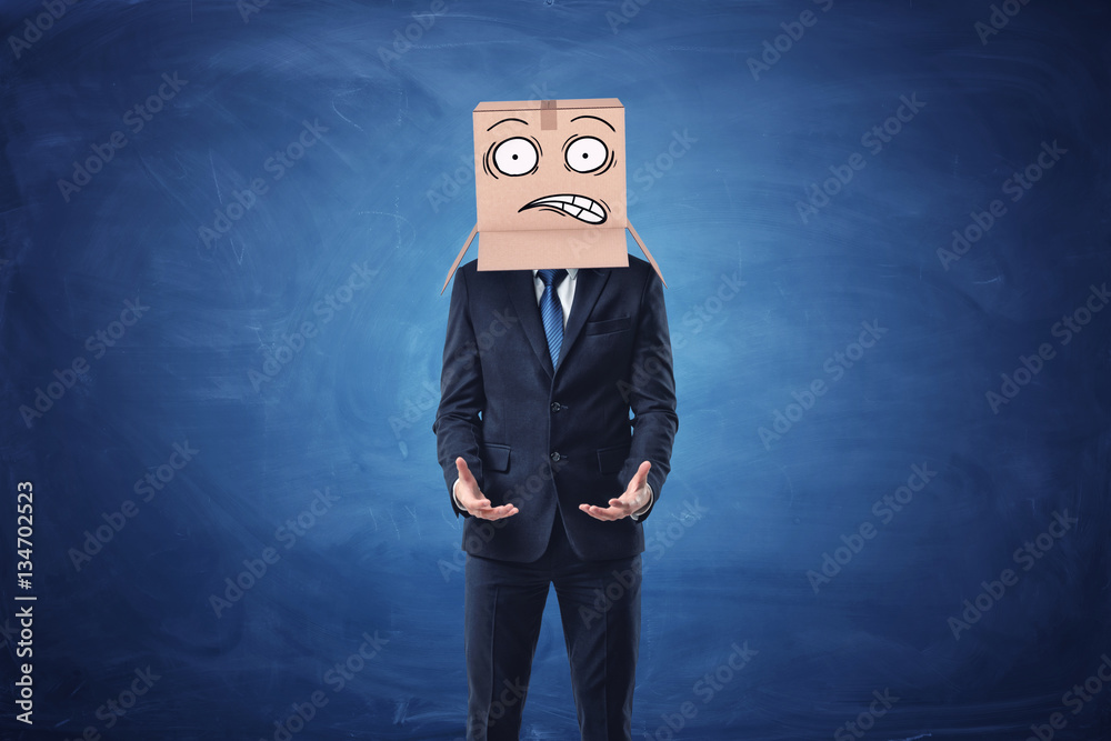 Businessman is wearing cardboard box with drawn shocked face on his head Businessman is wearing cardboard box with drawn shocked face on his head