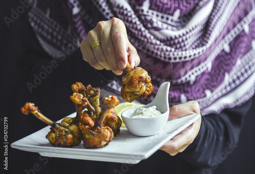 muslim woman show fried chicken / chicken boxing with white sauce photo