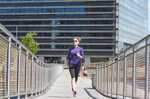 Sporty woman jogging at promenade on a sunny day