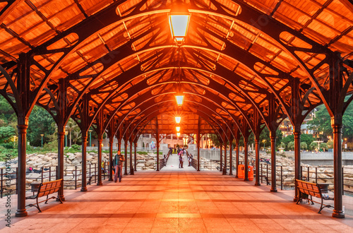 Blake Ferry Pier in Stanley Bay in Hong Kong is illuminated with red light lanterns hanging from the roof. Scenic perspective view in the evening