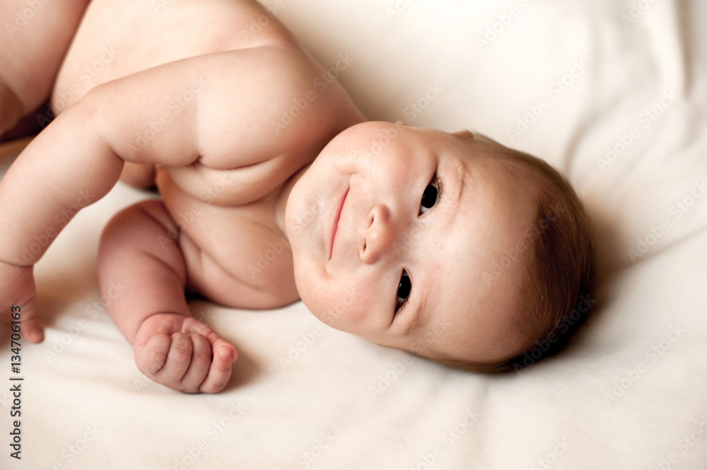 Soft picture of a beautiful baby boy laying on white bedding Soft picture of a beautiful baby boy laying on white bedding