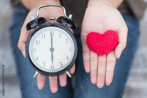 give time with love, showing retro clock and red heart on hand.