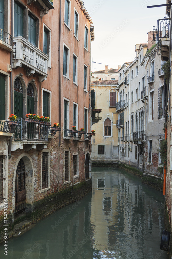 Vintage Venetian facades with small balconies reflects in canal