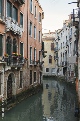 Vintage Venetian facades with small balconies reflects in canal