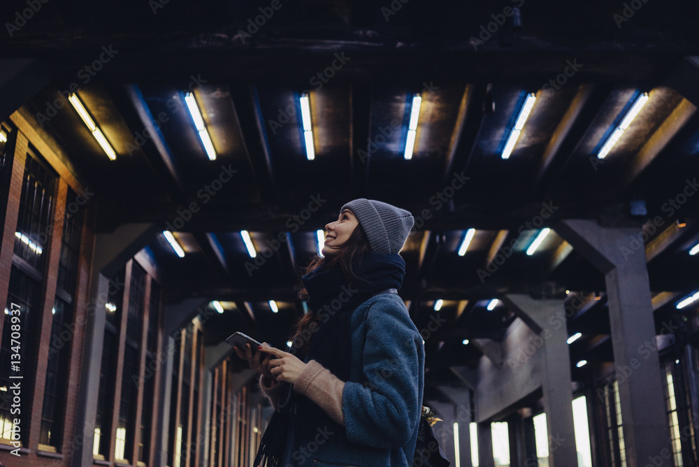 Obraz premium Woman in hat holding mobile phone and looking up