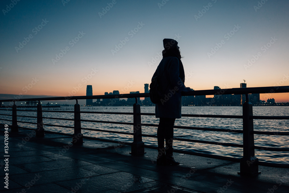 Fototapeta premium Silhouette of woman standing at the railing on a seafront