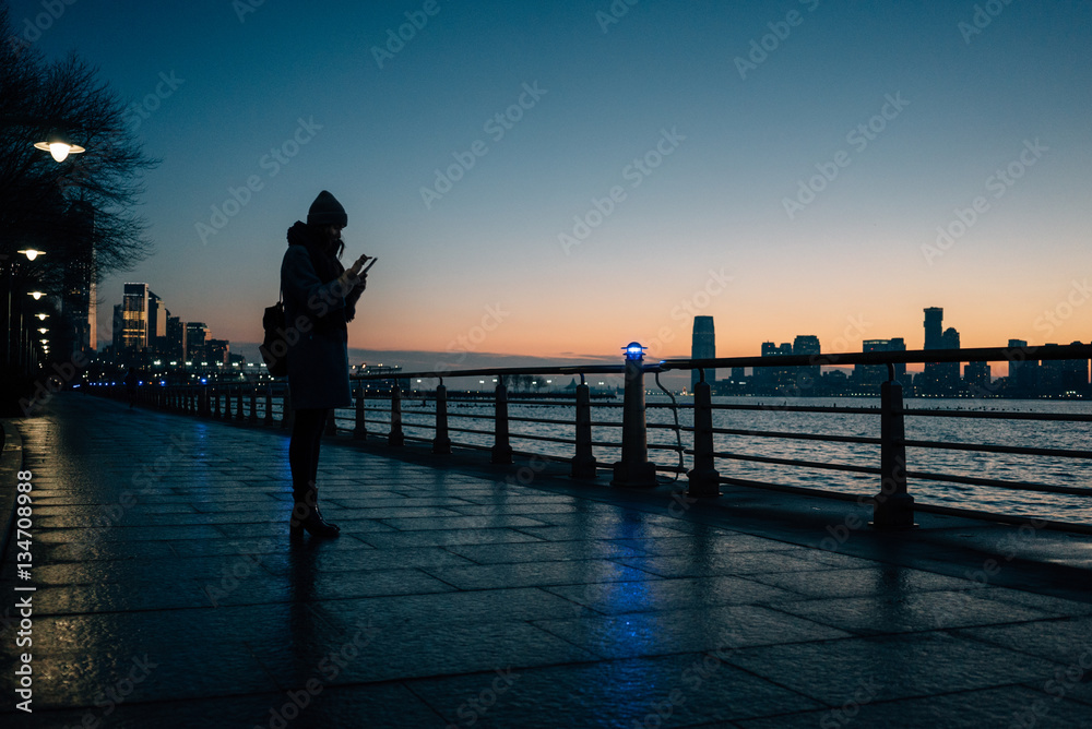 Woman standing on river pier and texting message