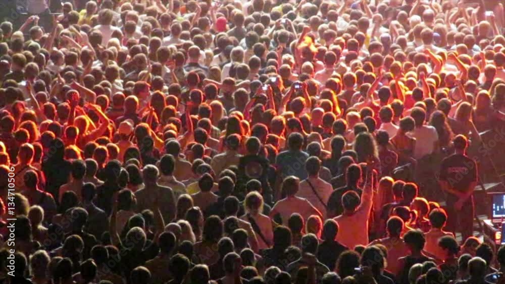 Cheering crowd at a music concert. Audience raising up hands and jumping