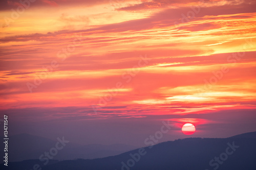 Red sunset in the mountains landscape with sunny beams. Dramatic scene. © 1tomm