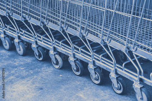 shopping cart in blue color tone for buy and sale in market background.